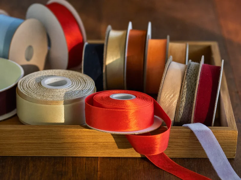 Bandspulen aus Satin, Samt und Jute auf einem Holztablett